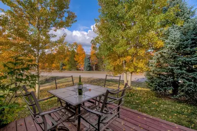 a table with a bottle of wine sitting on a deck at Beautiful Unit in Quiet Area with Shuttle to Slopes in Breckenridge