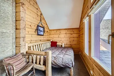 a log cabin bedroom with a bed and a window at Luxury Home for 12 with Hot Tub Sauna & Mtn Views in Breckenridge