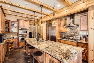 a kitchen with wooden cabinets and a large island with bar stools at Luxury Home for 12 with Hot Tub Sauna & Mtn Views in Breckenridge