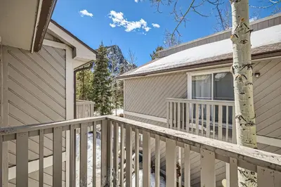 a house with a white deck next to a house at Charming 3 BDR for 8 in the Heart of the Rockies in Frisco
