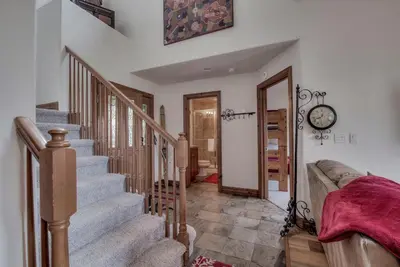 a living room with stairs and a clock on the wall at Spacious 4BR Near Trails with Shuttle to Slopes in Breckenridge