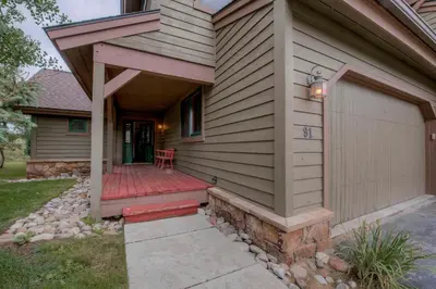 a house with a wooden porch with a garage at Spacious 4BR Near Trails with Shuttle to Slopes in Breckenridge