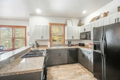 a kitchen with white cabinets and a black refrigerator at 3 BDR for 10 with Pool & Hot Tub Mins to Ski Lift in Dillon