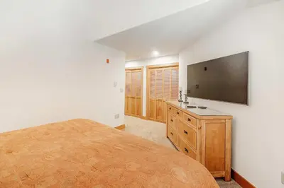 a bedroom with a large bed and a flat screen tv at 3 BDR for 10 with Pool & Hot Tub Mins to Ski Lift in Dillon