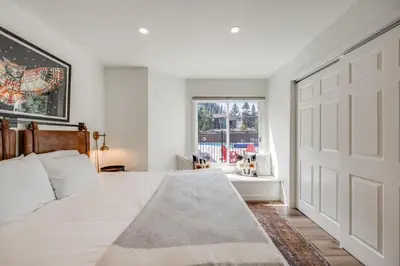 a bedroom with a white bed and a large door at Rock Wren Poolside - 3 BDR Condo in Keystone