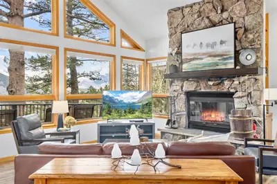 a living room with a stone fireplace and a table at Montane Luxury Vacation Rental at Windcliff home in Estes Park
