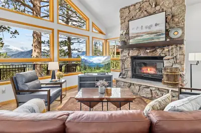 a living room with a large stone fireplace at Montane Luxury Vacation Rental at Windcliff home in Estes Park