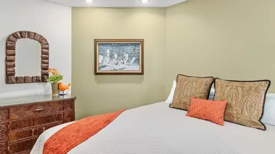 a bedroom with a bed with an orange blanket at Montane Luxury Vacation Rental at Windcliff home in Estes Park