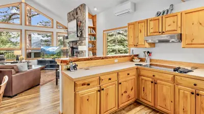 a kitchen with wooden cabinets and a living room at Montane Luxury Vacation Rental at Windcliff home in Estes Park