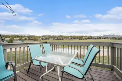 a patio table and chairs on a deck with a view at Townhouse w hot tub, gym & pool in Fraser