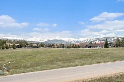 a field with mountains in the background with a road at Townhouse w hot tub, gym & pool in Fraser