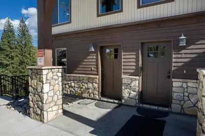 a house with brown doors and a stone wall at Townhome on Vasquez Creek #8 in Winter Park