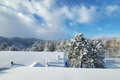 a snow covered slope with snow covered trees and clouds at Luxurious Rocky Mountain Retreat above Boulder in Nederland