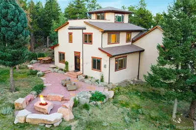 a house with a fire pit in front of it at Luxurious Rocky Mountain Retreat above Boulder in Nederland