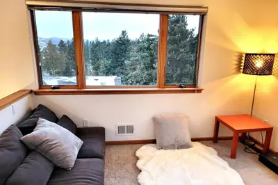 a living room with a couch and a large window at Luxurious Rocky Mountain Retreat above Boulder in Nederland