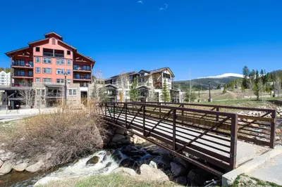 a bridge over a river in front of a building at Founders Pointe 4471 Ski In Ski Out Winter Park Resort in Winter Park