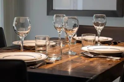 a wooden table with wine glasses and plates on it at Founders Pointe 4355 Ski In Ski Out Winter Park Resort in Winter Park