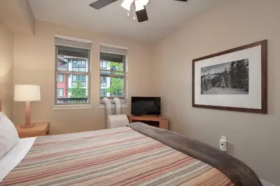a bedroom with a bed and a tv and two windows at Founders Pointe 4473 Ski In Ski Out Winter Park Resort in Winter Park