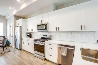 a kitchen with white cabinets and stainless steel appliances at 2 Mi to Ball Arena Townhome with Rooftop Patio in Denver