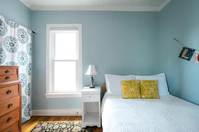 a bedroom with blue walls and a bed with yellow pillows at Charming Highlands Cottage - Walk to Shops & Eats in Denver