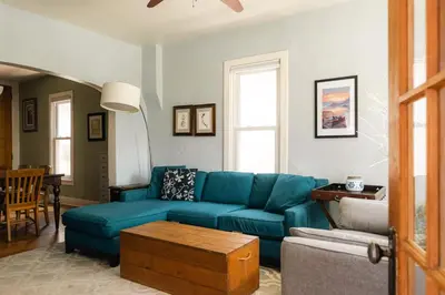 a living room with a blue couch and a table at Charming Highlands Cottage - Walk to Shops & Eats in Denver
