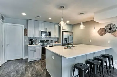a kitchen with white cabinets and a island with bar stools at Spacious and Quiet Retreat - Firepit and Yard in Denver