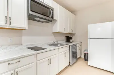 a kitchen with white cabinets and a white refrigerator at 12 Mi to Hospitals Modern Apartment in Aurora! in Aurora