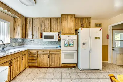 a kitchen with wooden cabinets and white appliances at Near Family-Friendly Attractions Northglenn Home! in Northglenn