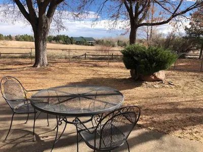 a glass table and chairs in a yard with trees at Large Home Near Boulder Fenced Yard 2 Dogs OK in Longmont