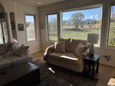 a living room with a couch and a table and windows at A Peaceful Slice of Heaven Near Boulder in Niwot