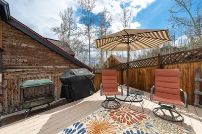 two chairs and an umbrella on a deck at West Portal Cabin cabin in Grand Lake