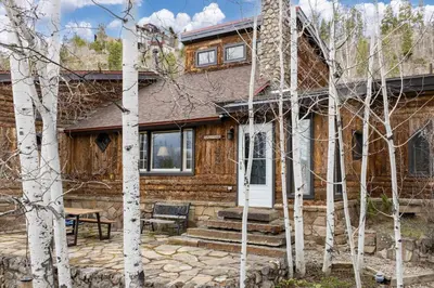 a log home with a white door and trees at West Portal Cabin cabin in Grand Lake