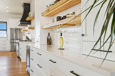 a kitchen with white cabinets and a counter with a bottle of wine at Bridle Ridge Retreat - Modern Comfort, Open Views in Timnath