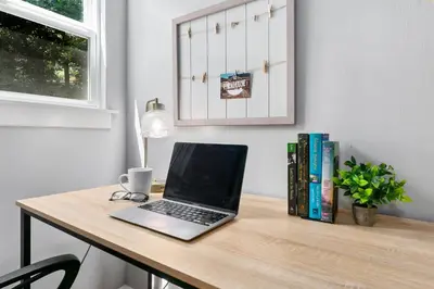 a laptop computer sitting on a desk with books at Urban Nest - Garage, Sunroom & Fenced Yard in Fort Collins
