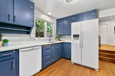 a kitchen with blue cabinets and a white refrigerator at Urban Nest - Garage, Sunroom & Fenced Yard in Fort Collins