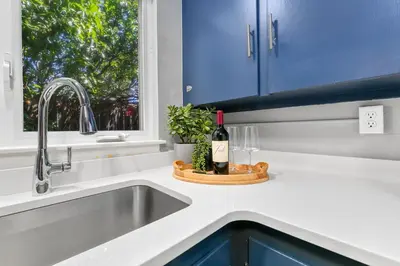 a kitchen counter with a sink and a bottle of wine at Urban Nest - Garage, Sunroom & Fenced Yard in Fort Collins
