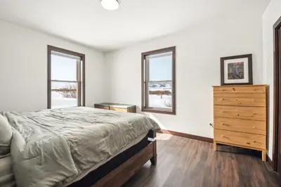 a bedroom with a bed and a dresser and two windows at 4br Mountain View Home - 5 Minutes To Granby Ranch in Granby