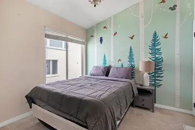 a bedroom with a bed with trees and birds on the wall at HUGE Downtown Getaway! w/Hot Tub in Arvada