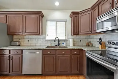 a kitchen with wooden cabinets and stainless steel appliances at HUGE Downtown Getaway! w/Hot Tub in Arvada