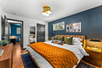a bedroom with a large bed with an orange blanket at Theater, Hot Tub, Mini Golf, Luxe Fun House in Centennial