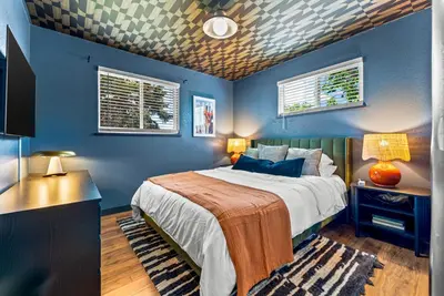 a blue bedroom with a bed and two windows at Theater, Hot Tub, Mini Golf, Luxe Fun House in Centennial