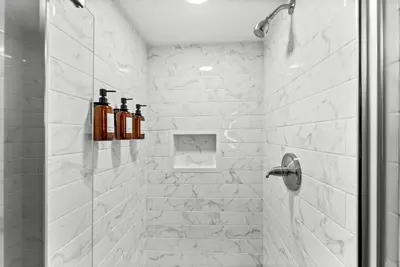 a bathroom with a shower with bottles on the wall at Theater, Hot Tub, Mini Golf, Luxe Fun House in Centennial