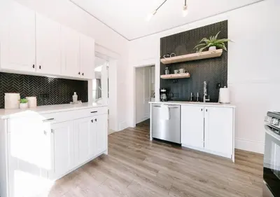 a white kitchen with white cabinets and a hardwood floor at Olde Town Ambler A Distinctive Walkable Retreat in Arvada