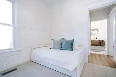 a white bedroom with a white bed with blue pillows at Olde Town Ambler A Distinctive Walkable Retreat in Arvada