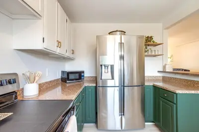 a kitchen with green cabinets and a stainless steel refrigerator at Near Shops and Eats Elegant Home in Wheat Ridge! in Wheat Ridge