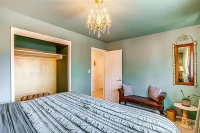 a bedroom with a bed and two chairs and a chandelier at Near Shops and Eats Elegant Home in Wheat Ridge! in Wheat Ridge