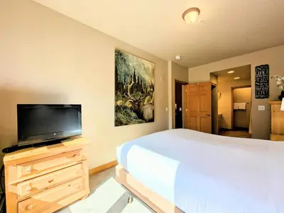 a bedroom with a large bed and a flat screen tv at Hidden River Lodge 5965 by SummitCove Lodging in Keystone