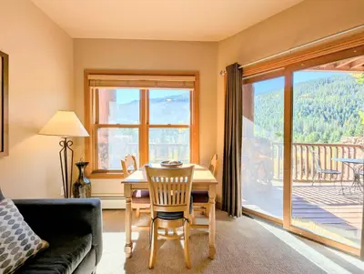 a living room with a table and chairs and a view of a deck at Hidden River Lodge 5965 by SummitCove Lodging in Keystone