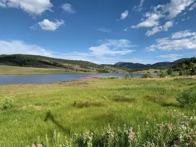 a field of grass with a lake in the background at Your Mountain Retreat in Loveland