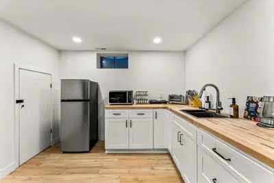 a kitchen with white cabinets and a stainless steel refrigerator at Arvada Hotspot Modern Vibes Sauna and Games in Arvada